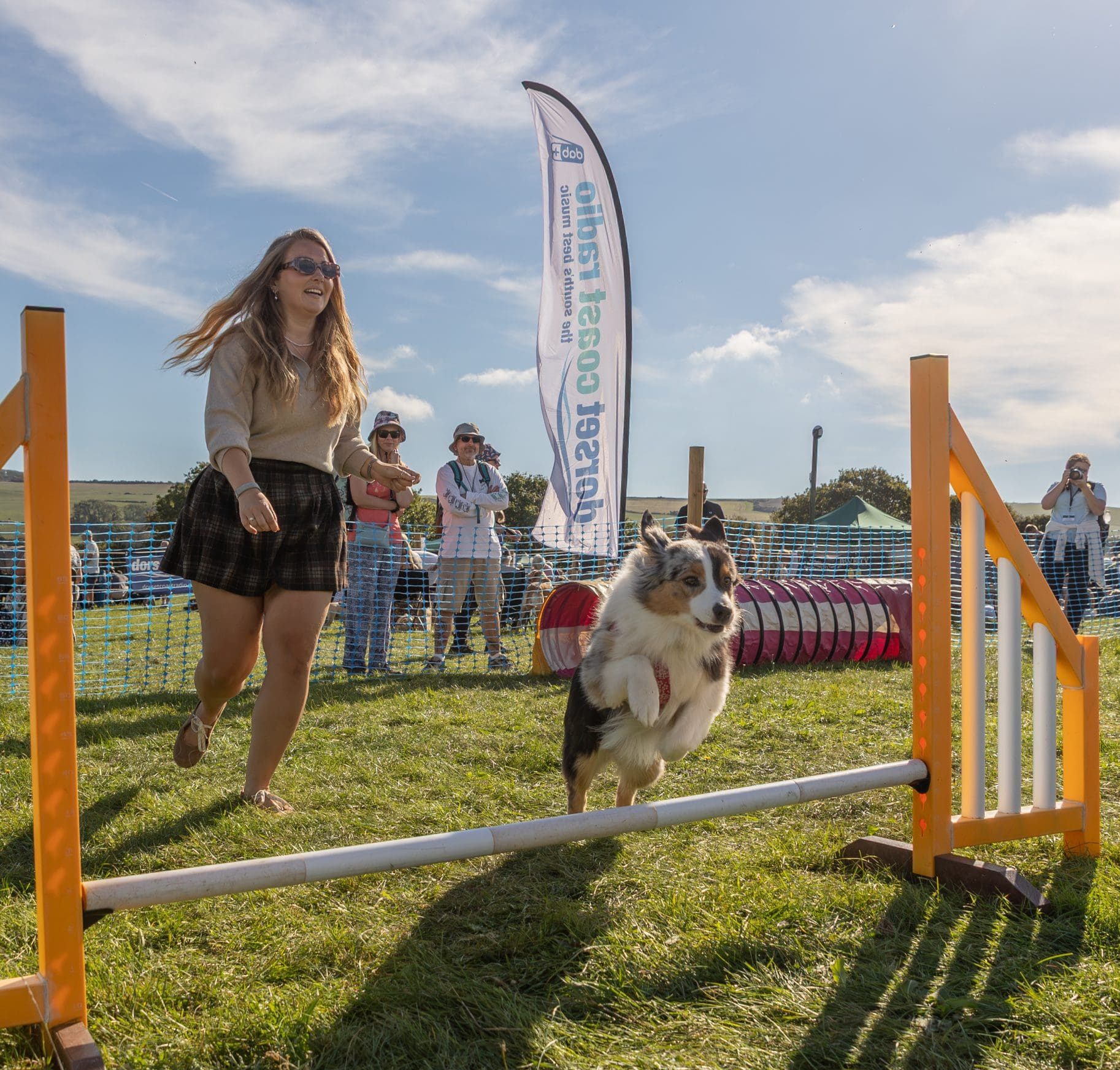 Country Fayre & Dog Show (1) A woman is sat on the grass behind a yellow Labrador, next to a prize at a dog show